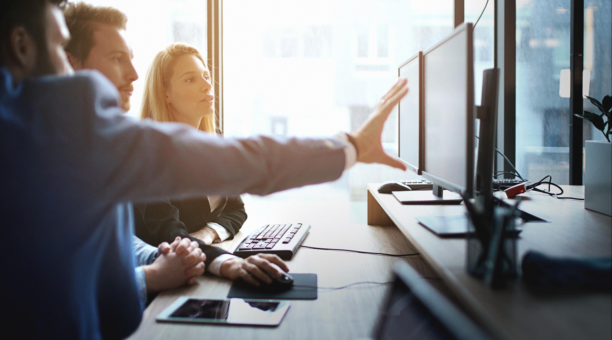 Two professionals reviewing information on large monitors