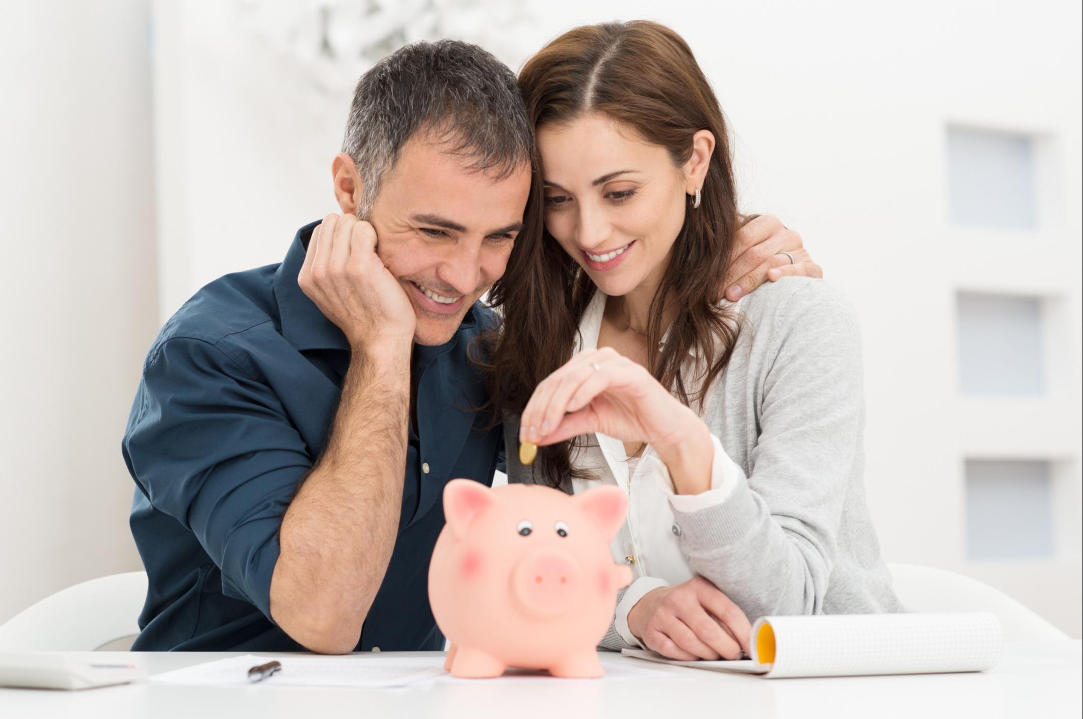 A couple adding money to a piggy bank